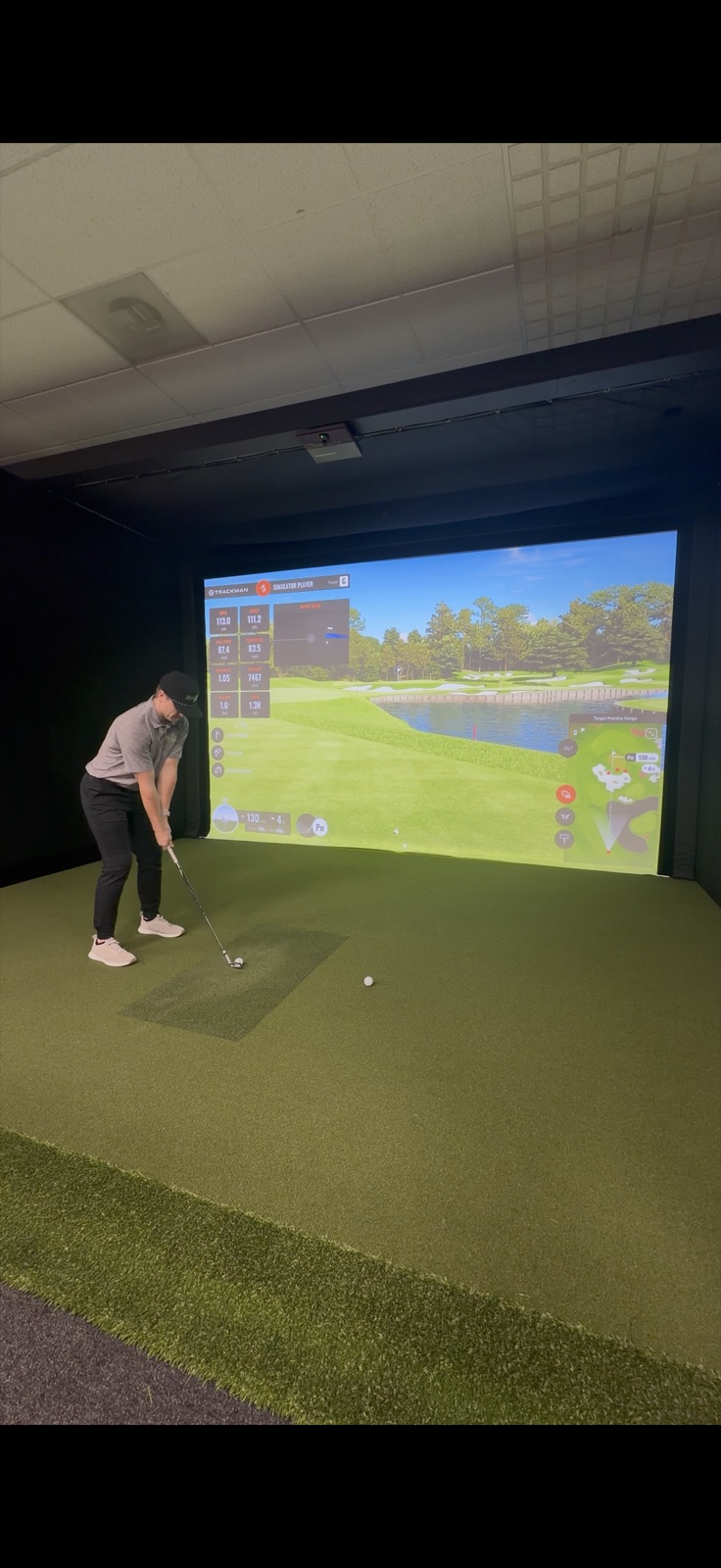 Golfer hitting a shot on a TrackMan simulator at Rain Check Golf