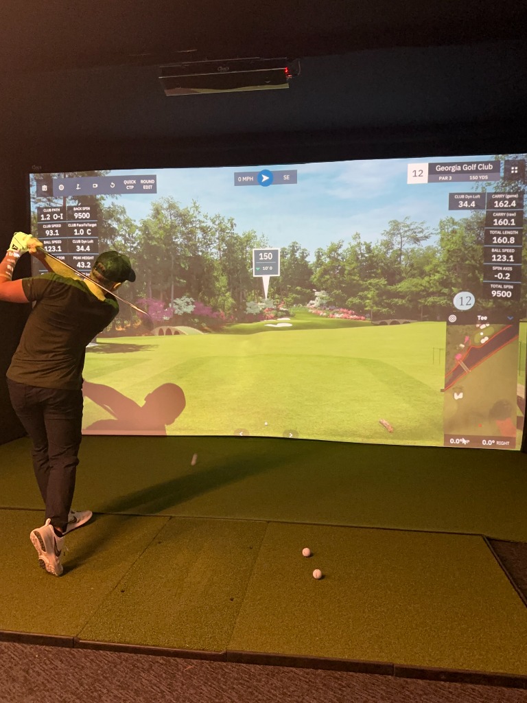 Golfer swinging in simulator bay